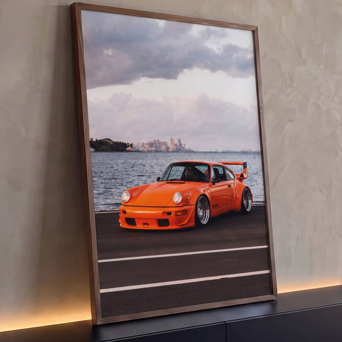 Quadro Decorativo Grande Carro Clássico para Sala Laranja | quadros decorativos para sala | carro esportivo laranja com aerofólio à beira da água e skyline ao fundo | Porao dos Quadros