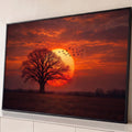 Árvore em silhueta diante de sol gigante, pássaros em voo e céu laranja no campo, quadro decorativo