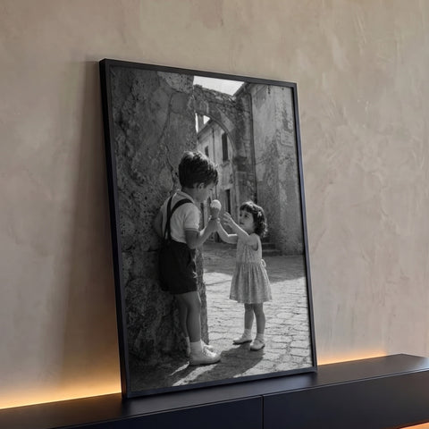 Menino oferece sorvete a menina em ruela de pedra com arco antigo, foto preto e branco, quadro decorativo
