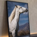 Cavalo tordilho branco de perfil com crina ao vento, céu azul e montanhas ao fundo, quadro decorativo