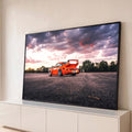 Porsche 911 laranja com aerofólio em asfalto sob céu roxo e rosa ao pôr do sol, quadro decorativo