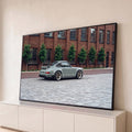 Porsche 911 clássico cinza com rodas douradas em rua de paralelepípedos e prédio de tijolos, quadro decorativo