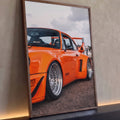 Quadro Decorativo Carro Clássico Laranja com Aerofólio | quadros decorativos para sala | carro esportivo laranja com rodas prateadas e aerofólio em vista lateral baixa | Porao dos Quadros