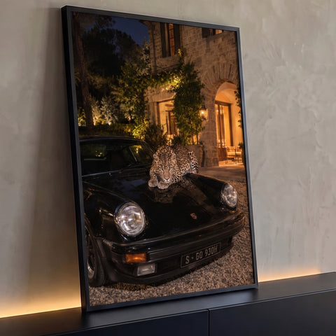 Quadro Decorativo Grande Leopardo para Sala Preto | quadros decorativos para sala | leopardo deitado sobre capô de carro preto em frente a casa noturna iluminada | Porao dos Quadros