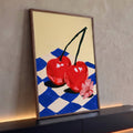 Quadro Decorativo Grande Cerejas Vermelhas para Área Gourmet | quadros decorativos para sala | duas cerejas vermelhas unidas sobre tecido xadrez azul e flor rosa | Porao dos Quadros