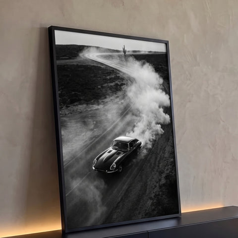 Carro esportivo clássico preto levantando poeira em estrada de terra no deserto com cacto, quadro decorativo