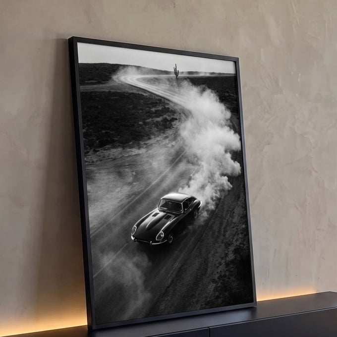 Carro esportivo clássico preto levantando poeira em estrada de terra no deserto com cacto, quadro decorativo