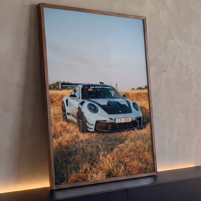 Porsche 911 GT3 RS azul claro com aerofólio em campo de grama seca sob céu azul, quadro decorativo