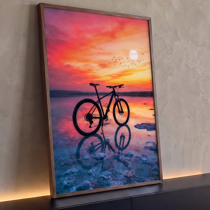Mountain bike em silhueta refletida em salina sob pôr do sol rosa e laranja com pássaros, quadro decorativo