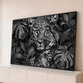 Leopardo de olhar intenso entre folhas de monstera em preto e branco, quadro decorativo