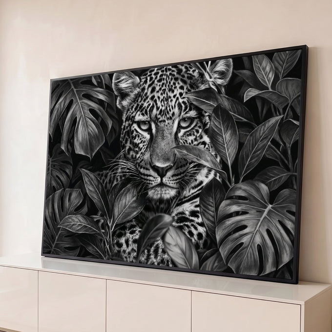 Leopardo de olhar intenso entre folhas de monstera em preto e branco, quadro decorativo