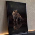 Leopardo sentado à beira d'água sob a lua, com reflexo na água escura, quadro decorativo