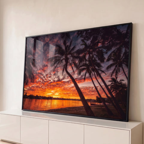 Palmeiras em silhueta sob céu laranja e vermelho do pôr do sol refletido no rio, quadro decorativo