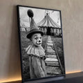 Menino vestido de palhaço com gola de renda diante de tenda de circo em preto e branco, quadro decorativo