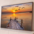 Pôr do sol laranja sobre lago calmo, píer de madeira e gaivotas voando em silhueta, quadro decorativo