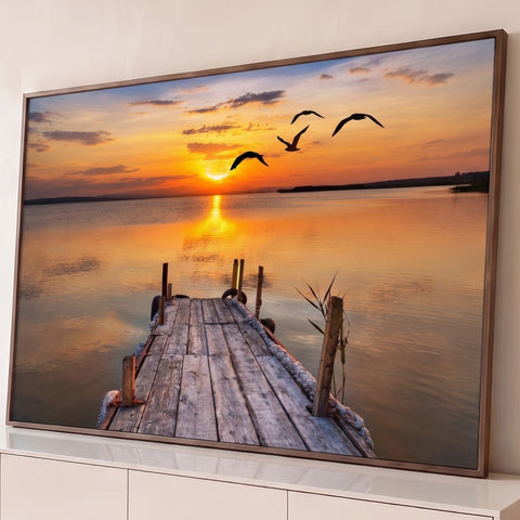 Pôr do sol laranja sobre lago calmo, píer de madeira e gaivotas voando em silhueta, quadro decorativo