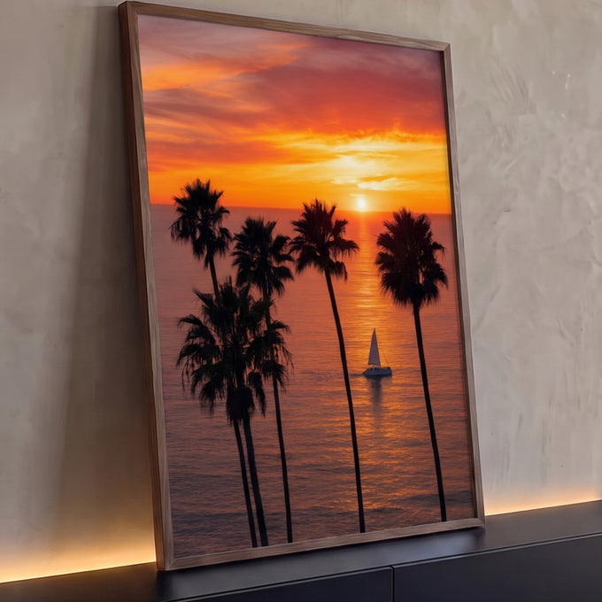 Pôr do sol laranja no mar com palmeiras altas em silhueta e veleiro branco ao centro, quadro decorativo
