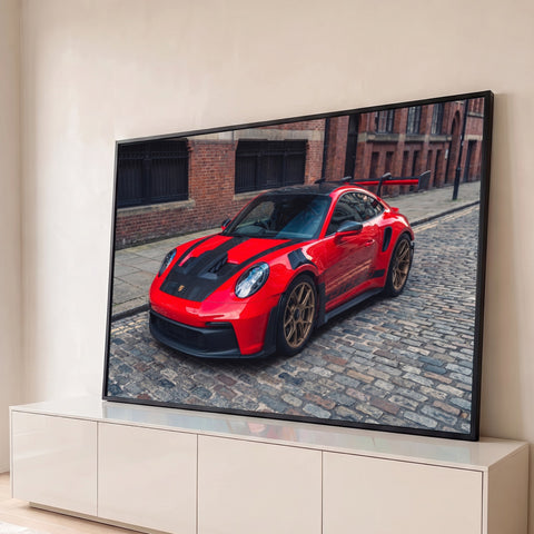 Porsche 911 GT3 RS vermelho com rodas douradas em rua de paralelepípedos e prédio de tijolos, quadro decorativo