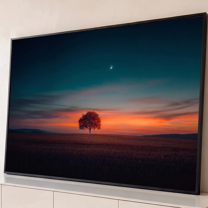 Árvore solitária em campo ao pôr do sol laranja, céu azul-petróleo e lua crescente, quadro decorativo
