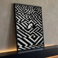 Rosto de olhos fechados surgindo entre degraus com padrão zigue-zague preto e branco, quadro decorativo