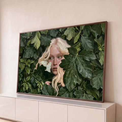 Mulher loira de sardas espiando entre folhagem verde com borboleta branca no rosto, quadro decorativo