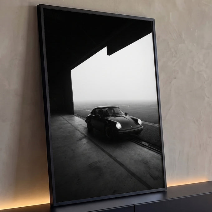 Quadro Decorativo Grande Carro Clássico Preto para Sala | quadros decorativos para sala | carro esportivo clássico preto estacionado na saída de um hangar com neblina ao fundo | Porao dos Quadros