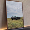 Mustang clássico preto estacionado em campo de grama sob céu nublado, quadro decorativo