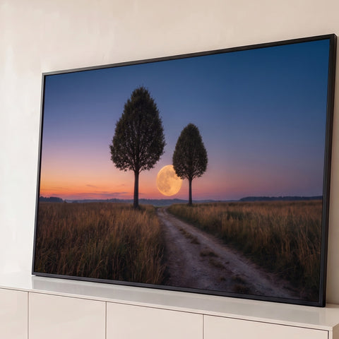 Lua cheia dourada entre duas árvores sobre campo e estrada de terra ao anoitecer, quadro decorativo
