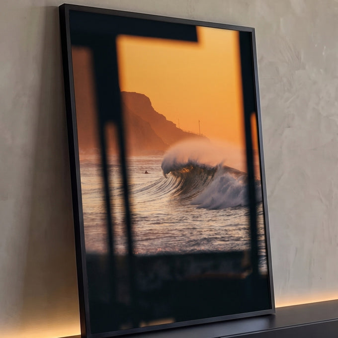 Onda gigante quebrando no mar ao pôr do sol laranja com falésia, vista de janela escura, quadro decorativo