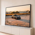 Porsche 911 clássico cinza rebaixado sobre areia com capim dourado e palmeiras ao pôr do sol, quadro decorativo