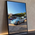 Porsche 911 clássico azul-claro estacionado sob céu azul com efeito pintura a óleo, quadro decorativo