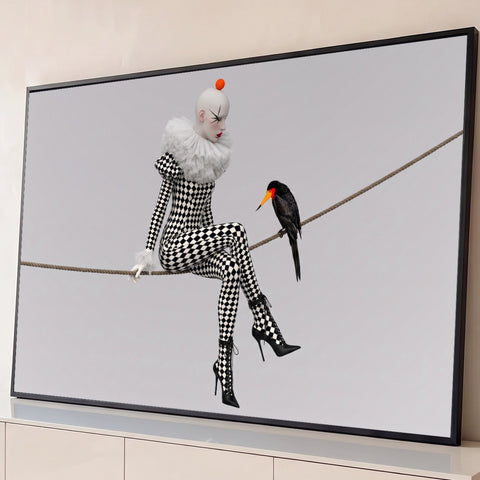 Mulher arlequim em xadrez preto e branco sentada numa corda ao lado de pássaro preto, quadro decorativo