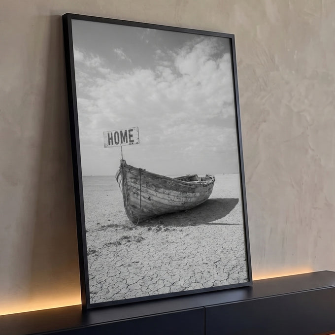Barco de madeira envelhecido com placa HOME sobre terra rachada em preto e branco, quadro decorativo
