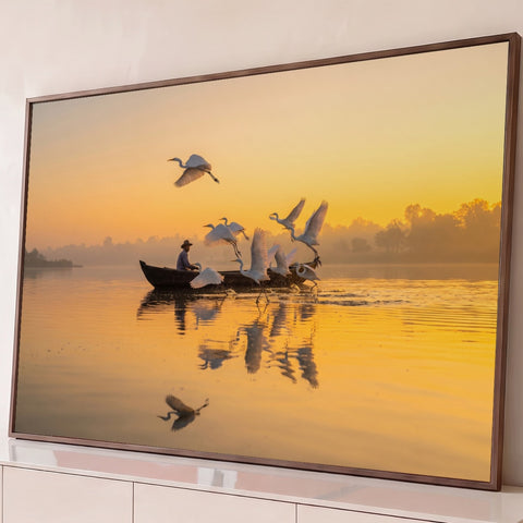 Garças brancas voando sobre lago laranja ao amanhecer com pescador em barco de madeira, quadro decorativo