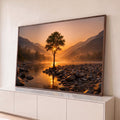 Quadro Decorativo Grande Árvore Solitária Rio para Sala | quadros decorativos para sala | árvore solitária sobre pedras à beira de rio com sol poente entre galhos e montanhas ao fundo | Porao dos Quadros