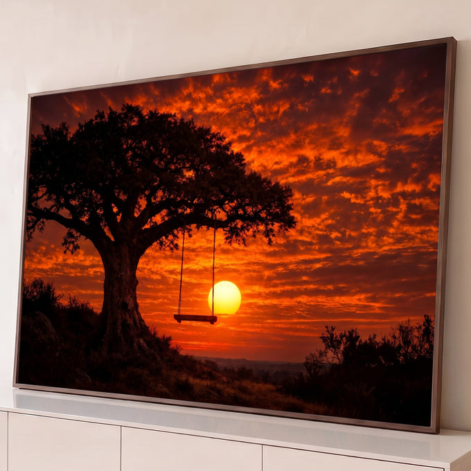 Árvore em silhueta com balanço de madeira diante do sol se pondo em céu laranja intenso, quadro decorativo