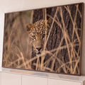 Quadro Decorativo Grande Leopardo Felino para Sala Marrom | quadros decorativos para sala | leopardo espreitando atrás de tronco de árvore com olhar intenso entre galhos secos | Porao dos Quadros