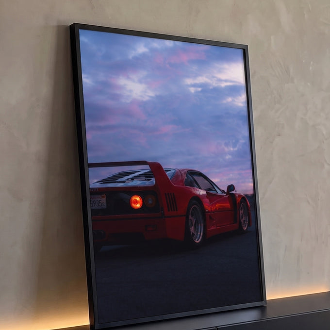 Carro esportivo vermelho clássico de traseira com lanterna acesa sob céu roxo e rosa do crepúsculo, quadro decorativo