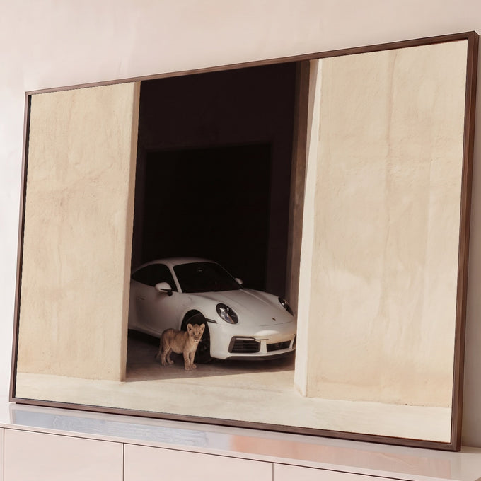 Porsche 911 branco em portal de estuque bege com filhote de leão à frente, fotografia minimalista, quadro decorativo