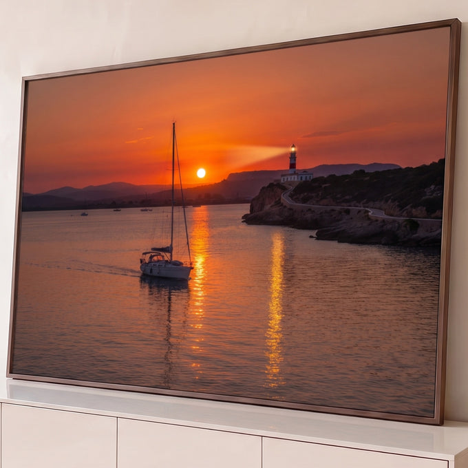 Quadro Decorativo Grande Veleiro e Farol Laranja para Sala | quadros decorativos para sala | veleiro navegando ao pôr do sol com farol aceso sobre penhasco rochoso | Porao dos Quadros