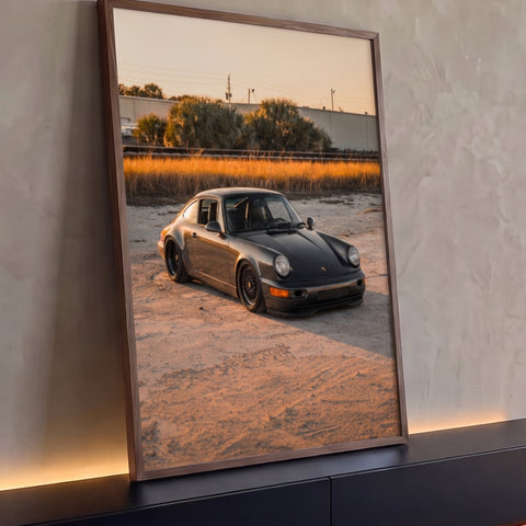Porsche 911 clássico grafite na areia ao entardecer com capim dourado ao fundo, quadro decorativo