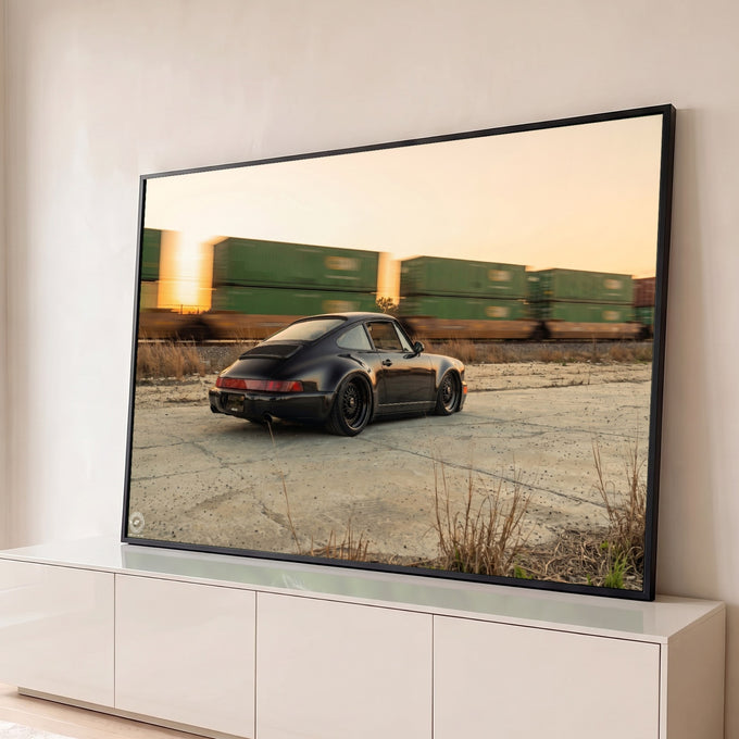 Porsche 911 clássico preto rebaixado, com trem de contêineres passando ao pôr do sol, quadro decorativo