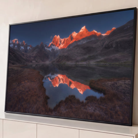 Picos nevados alaranjados pelo sol refletidos em lago de montanha com campo marrom, quadro decorativo