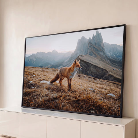 Raposa vermelha em campo de grama seca com picos rochosos das montanhas ao fundo, quadro decorativo