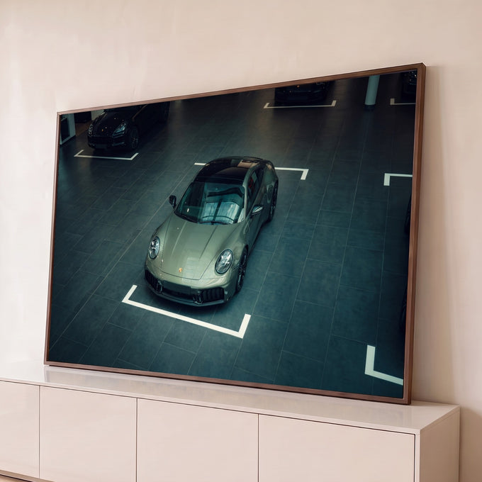 Porsche 911 verde oliva visto do alto em showroom de piso escuro com faixas brancas, quadro decorativo