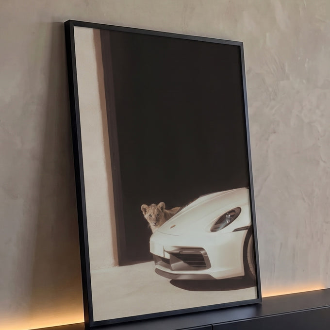 Quadro Decorativo Grande Filhote de Leão para Sala Preto | quadros decorativos para sala | filhote de leão espiando atrás de carro esportivo branco em vão escuro | Porao dos Quadros