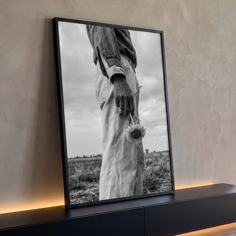 Quadro Decorativo Girassol na Mão em Preto e Branco | quadros decorativos para sala | mão segurando girassol invertido em fotografia preto e branco num campo aberto | Porao dos Quadros