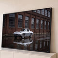 Corvette Stingray clássico prata refletido no chão molhado diante de galpão de tijolos, quadro decorativo