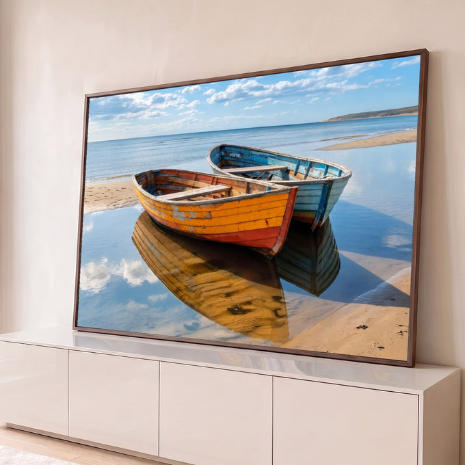 Dois barcos de madeira laranja e azul na areia da praia com reflexo no mar calmo, quadro decorativo