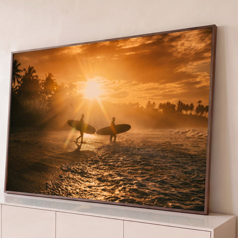 Dois surfistas em silhueta com pranchas entrando no mar ao pôr do sol entre palmeiras, quadro decorativo